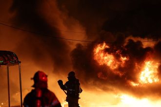 Firefighters extinguish a fire at a factory building that has been engulfed in a wildfire in Uiseong, South Korea, Saturday, March 22, 2025.