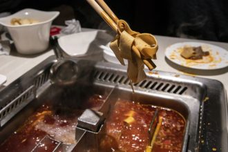 A customer pulls some tofu out of a hotpot at a Haidilao restaurant in Shanghai.