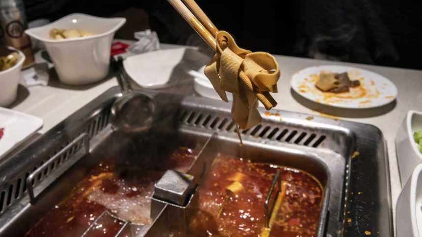 A customer pulls some tofu out of a hotpot at a Haidilao restaurant in Shanghai.