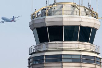 An American Airlines airplane takes off past the air traffic control tower at Ronald Reagan Washington National Airport in Arlington, Virginia, on January 11, 2023.