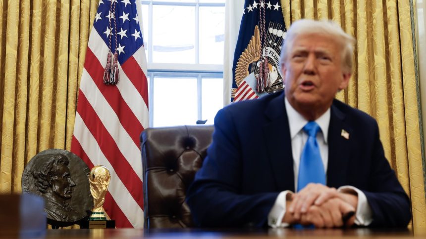 A World Cup trophy is visible behind US President Donald Trump as he speaks with reporters in the Oval Office of the White House on February 4.