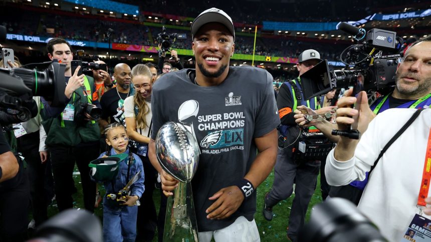 Saquon Barkley celebrates with the Vince Lombardi Trophy after beating the Kansas City Chiefs at Super Bowl LIX.