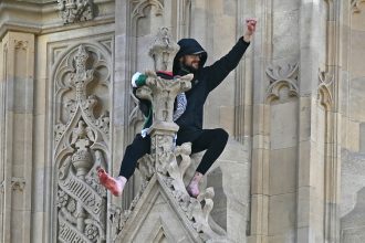 A protestor has climbed several meters up the Elizabeth Tower, commonly known as "Big Ben," and stood barefoot on a ledge holding a Palestinian flag.