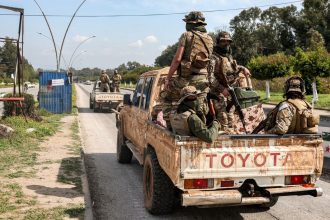 Security forces loyal to the interim Syrian government ride in the back of a vehicle in Syria's western city of Latakia on Sunday.