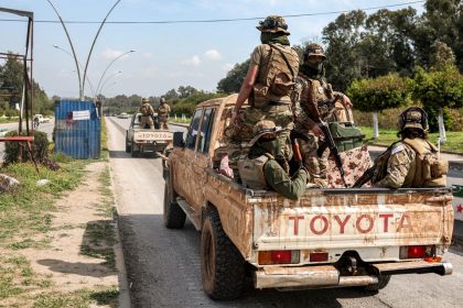 Security forces loyal to the interim Syrian government ride in the back of a vehicle in Syria's western city of Latakia on Sunday.