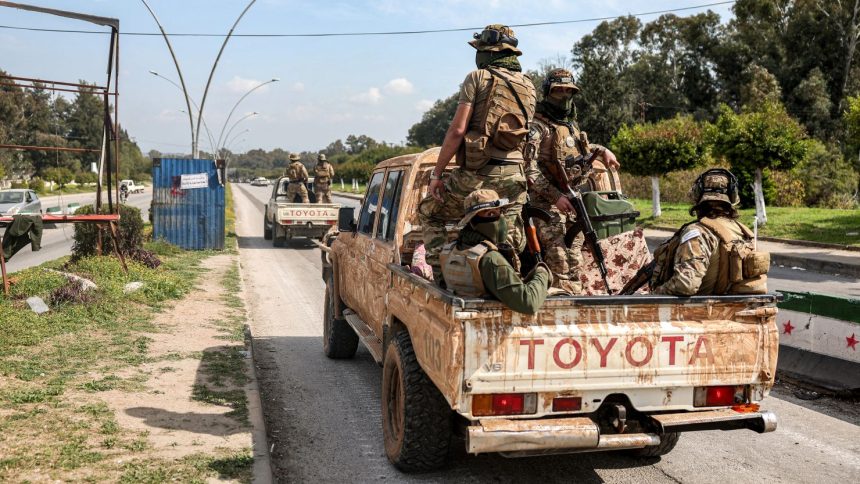 Security forces loyal to the interim Syrian government ride in the back of a vehicle in Syria's western city of Latakia on Sunday.