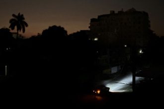 Car lights illuminate a street during a general blackout in Havana on March 14, 2025.