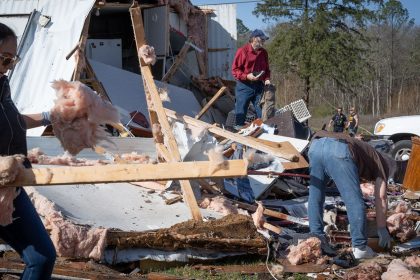 Tim Striegel, in red shirt (center), goes though his damaged belongings while volunteers help him clean up the morning after his mobile home was hit by a tornado on Sunday in Calera, Alabama.