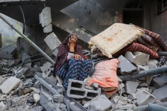 A Palestinian woman sits on the rubble of her house, destroyed in an Israeli strike, in the Nuseirat refugee camp in central Gaza on Tuesday.