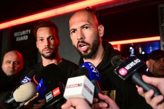 Andrew Tate, right and his brother Tristan, center, speak to the media as they arrive in Bucharest, Romania back from US, on Saturday.