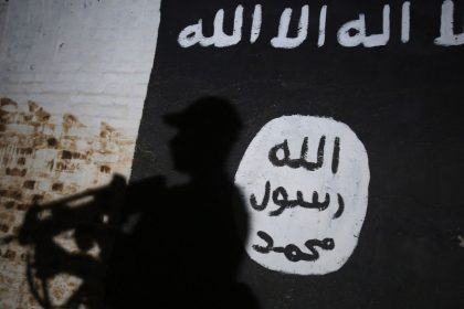 TOPSHOT - A member of the Iraqi forces walks past a mural bearing the logo of the Islamic State (IS) group in a tunnel that was reportedly used as a training centre by the jihadists, on March 1, 2017, in the village of Albu Sayf, on the southern outskirts of Mosul. Iraqi forces launched a major push on February 19 to recapture the west of Mosul from the Islamic State jihadist group, retaking the airport and then advancing north. (Photo by AHMAD AL-RUBAYE / AFP) (Photo by AHMAD AL-RUBAYE/AFP via Getty Images)