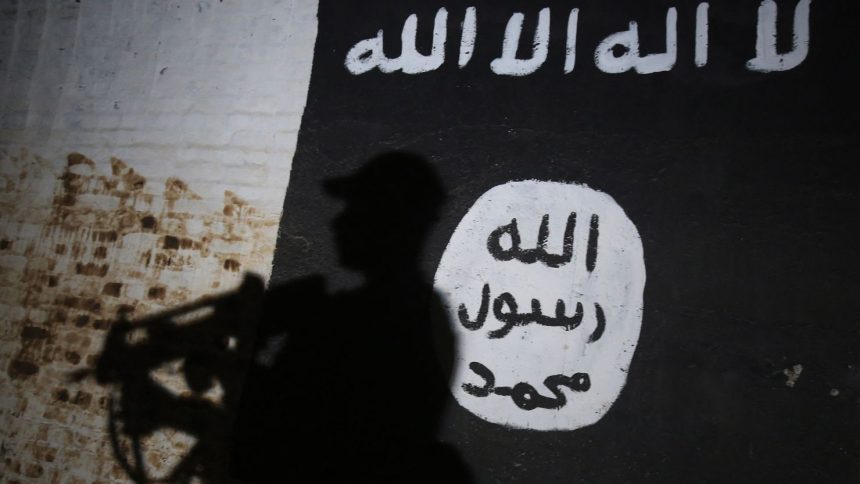 TOPSHOT - A member of the Iraqi forces walks past a mural bearing the logo of the Islamic State (IS) group in a tunnel that was reportedly used as a training centre by the jihadists, on March 1, 2017, in the village of Albu Sayf, on the southern outskirts of Mosul. Iraqi forces launched a major push on February 19 to recapture the west of Mosul from the Islamic State jihadist group, retaking the airport and then advancing north. (Photo by AHMAD AL-RUBAYE / AFP) (Photo by AHMAD AL-RUBAYE/AFP via Getty Images)