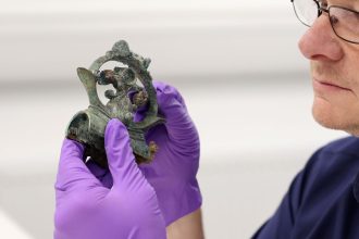 Tom Moore, head of archaeology at Durham University, holding a decorative copper alloy finial, which was part of the hoard.