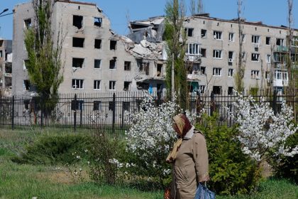 A woman walks past a war-damaged apartment building in Avdiivka, a Russian-occupied town in Ukraine's eastern Donetsk region, on April 20, 2025.