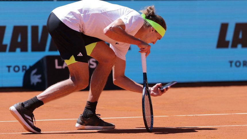 Alex Zverev takes a picture of the ball mark with his phone.