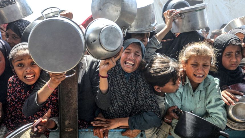 Displaced Palestinians receive hot meals distributed by aid organizations in al-Mawasi area of Khan Younis, Gaza on Tuesday.