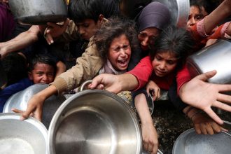 Palestinians wait to receive food cooked by a charity kitchen, in Jabalya, northern Gaza, on Wednesday.