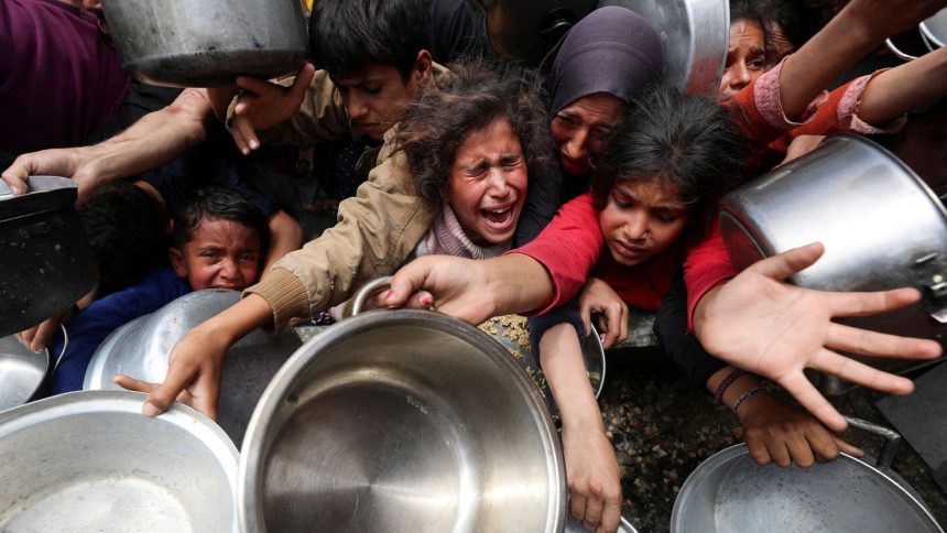 Palestinians wait to receive food cooked by a charity kitchen, in Jabalya, northern Gaza, on Wednesday.