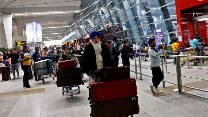 Travelers push luggage carts through New Delhi's Indira Gandhi International Airport.
