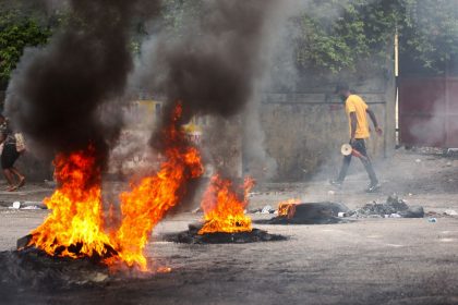People walk past a burning barricade during a protest against insecurity, in Port-au-Prince, Haiti, on April 16.