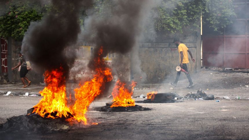 People walk past a burning barricade during a protest against insecurity, in Port-au-Prince, Haiti, on April 16.