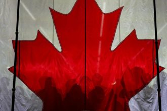 Supporters cast shadows on a Canadian flag as they gather prior to an election campaign event for Conservative Party of Canada's leader Pierre Poilievre, in Vaughan, Ontario, Canada April 22, 2025.