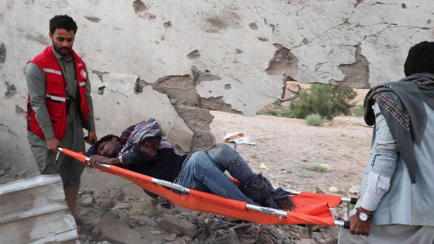 Rescuers carry an injured African migrant after a strike hit a detention centre hosting African migrants, in Saada, Yemen, on April 28, 2025.