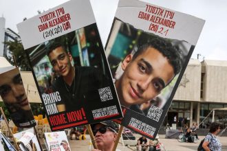 A person holds the pictures of the hostages, on the day Israeli-American hostage Edan Alexander, who was kidnapped during the deadly October 7 attack, is expected to be released from captivity by Hamas in Gaza, in Tel Aviv, Israel May 12, 2025. REUTERS/Ronen Zvulun