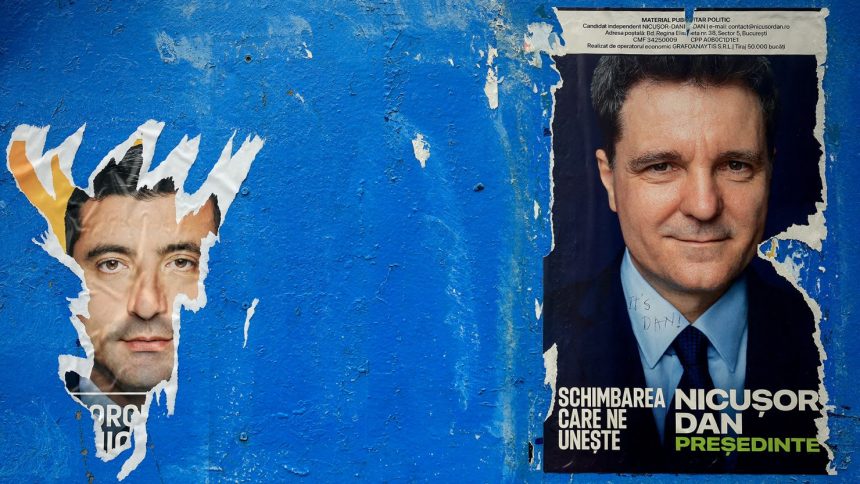 A torn poster featuring presidential candidate George Simion is seen next to one of Nicusor Dan ahead of the second round of the presidential elections, in Bucharest, Romania, on May 16, 2025.