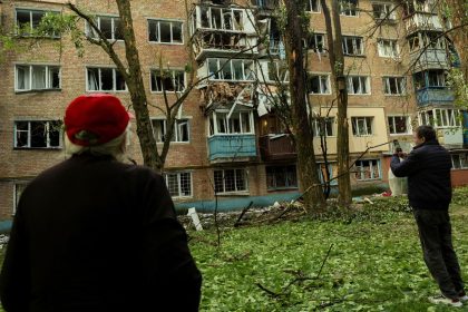 Residents look at an apartment building in Kyiv, Ukraine, that was damaged during a Russian attack, on Saturday.