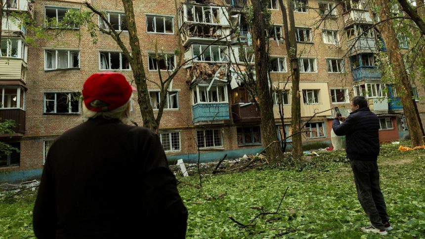 Residents look at an apartment building in Kyiv, Ukraine, that was damaged during a Russian attack, on Saturday.