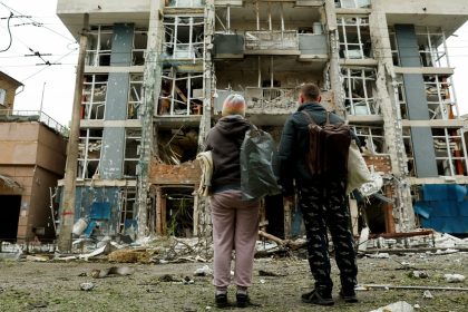 Residents look at a Kyiv apartment building that was damaged in a Russian drone strike on May 25, 2025.