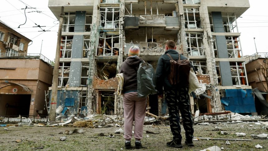 Residents look at a Kyiv apartment building that was damaged in a Russian drone strike on May 25, 2025.