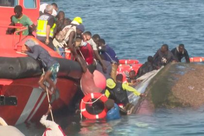 Emergency workers try to rescue migrants from the water after their boat capsized as rescuers were escorting it to port in Spain's Canary Islands on May 28, 2025.