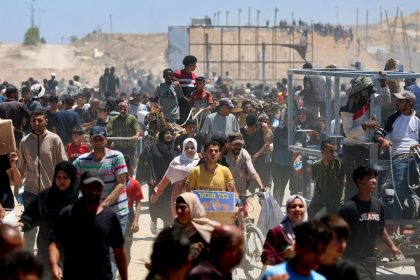 People gather as Palestinians receive aid supplies from the US-backed Gaza Humanitarian Foundation, in the central Gaza Strip, May 29, 2025.