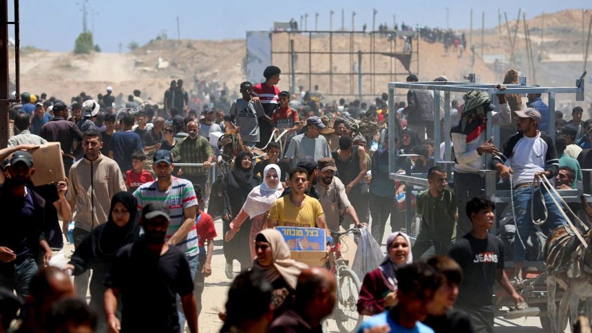 People gather as Palestinians receive aid supplies from the US-backed Gaza Humanitarian Foundation, in the central Gaza Strip, May 29, 2025.