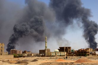 A man walks while smoke rises above buildings after aerial bombardment, during clashes between the paramilitary Rapid Support Forces and the army in Khartoum North, Sudan, May 1, 2023. REUTERS/Mohamed Nureldin Abdallah     TPX IMAGES OF THE DAY