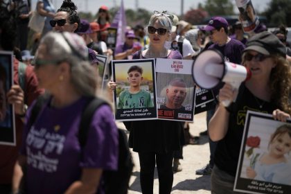 People hold pictures of hostages held by Hamas and children killed by Israeli bombardment in the Gaza Strip at a protest near the Israeli-Gaza border in Sderot, southern Israel, Friday, May 23, 2025.