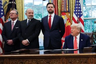 President Donald Trump is flanked by aides as he makes an announcement about a trade deal with the UK in the Oval Office at the White House in Washington, DC, on May 8.