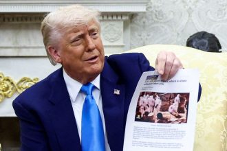 President Donald Trump shows a copy of an article in the Oval Office of the White House in Washington, DC, on May 21.