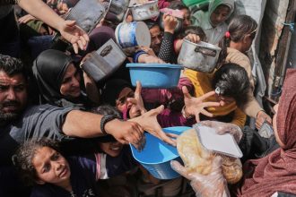 Palestinians clamber to receive donated food at a distribution center in Beit Lahiya in the northern Gaza Strip on April 7.