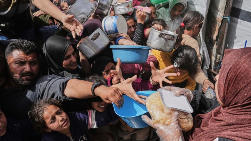 Palestinians clamber to receive donated food at a distribution center in Beit Lahiya in the northern Gaza Strip on April 7.
