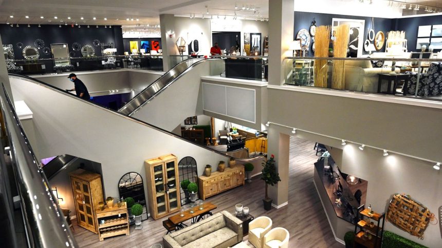 In this 2020 photo, a worker goes up an escalator at Jordan's Furniture Store at the Maine Mall in South Portland, Maine.