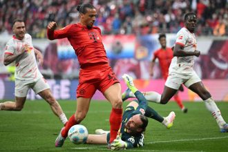 Leroy Sane of Bayern Munich is brought down by Maarten Vandevoordt of RB Leipzig during the Bundesliga match between RB Leipzig and FC Bayern München at Red Bull Arena on May 3, 2025 in Leipzig, Germany.