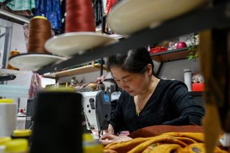 A woman sews clothing at the Keqiao China Textile City, one of the biggest textile markets in Asia, in Shaoxing in China's eastern Zhejiang province on May 8.