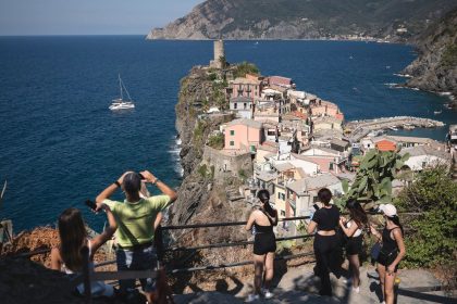 Tourists look out from a hillside in Vernazza in the Cinque Terre National Park, near La Spezia, Italy.