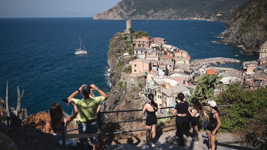 Tourists look out from a hillside in Vernazza in the Cinque Terre National Park, near La Spezia, Italy.