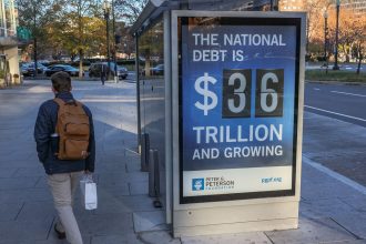 A bus shelter in Washington, DC, displays a billboard that says the US national debt is $36 trillion dollars in December 2024.
