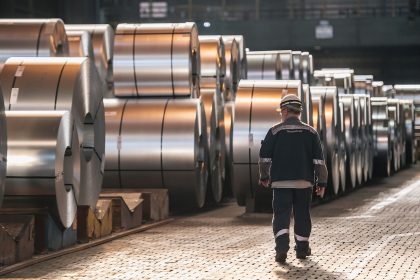 A worker walks past coils of finished steel at the Thyssenkrupp steel mill on March 20 in Duisburg, Germany.