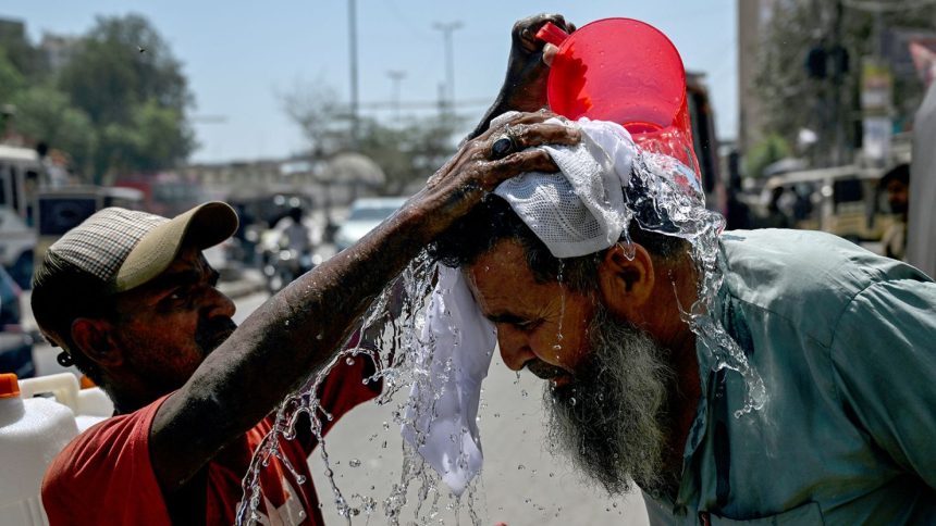 A volunteer pours water on a pedestrian's head to cool off during a hot summer day along a street in Karachi on April 5, 2025.